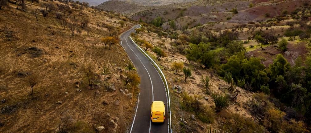 A DHL van driving down a country road.