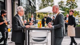 Two male colleagues have lunch outdoors