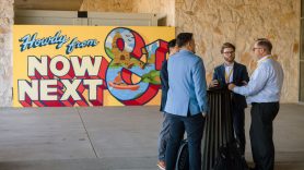 Delegates converse in front of mural