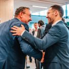 Two male colleagues network joyfully at DHL event