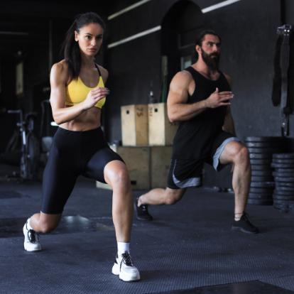 Two people exercise in a gym in exercise clothes
