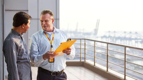 A DHL employee talking to a person, holding a clipboard