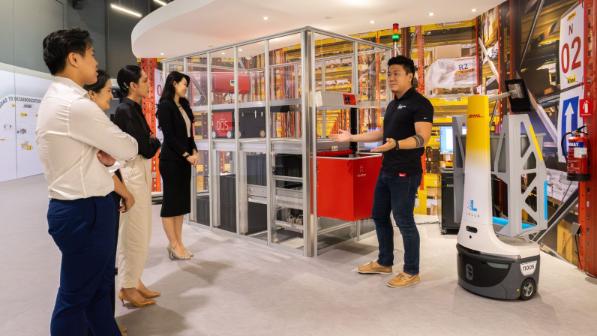 A DHL employee showcasing a Locus Robot to customers.
