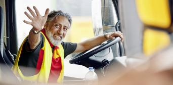 DHL employee waves out of the window of his van