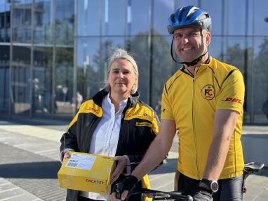 Vorständin Nikola Hagleitner am Bonner Post Tower mit einem Mitglied des Radsportteams der DHL Group