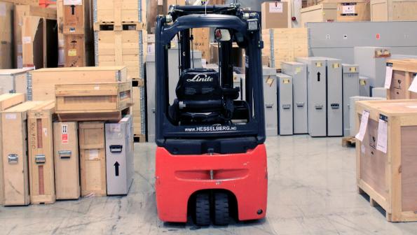 A forklift parked in a warehouse surrounded by wooden crates.