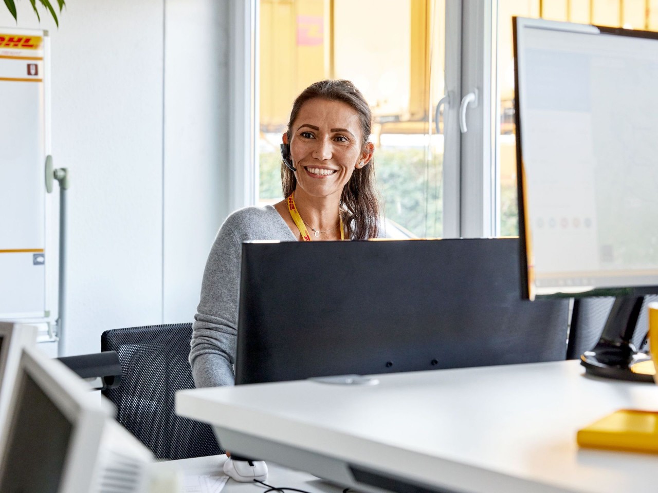 medarbejder-med-headset-arbejder-ved-en-computer