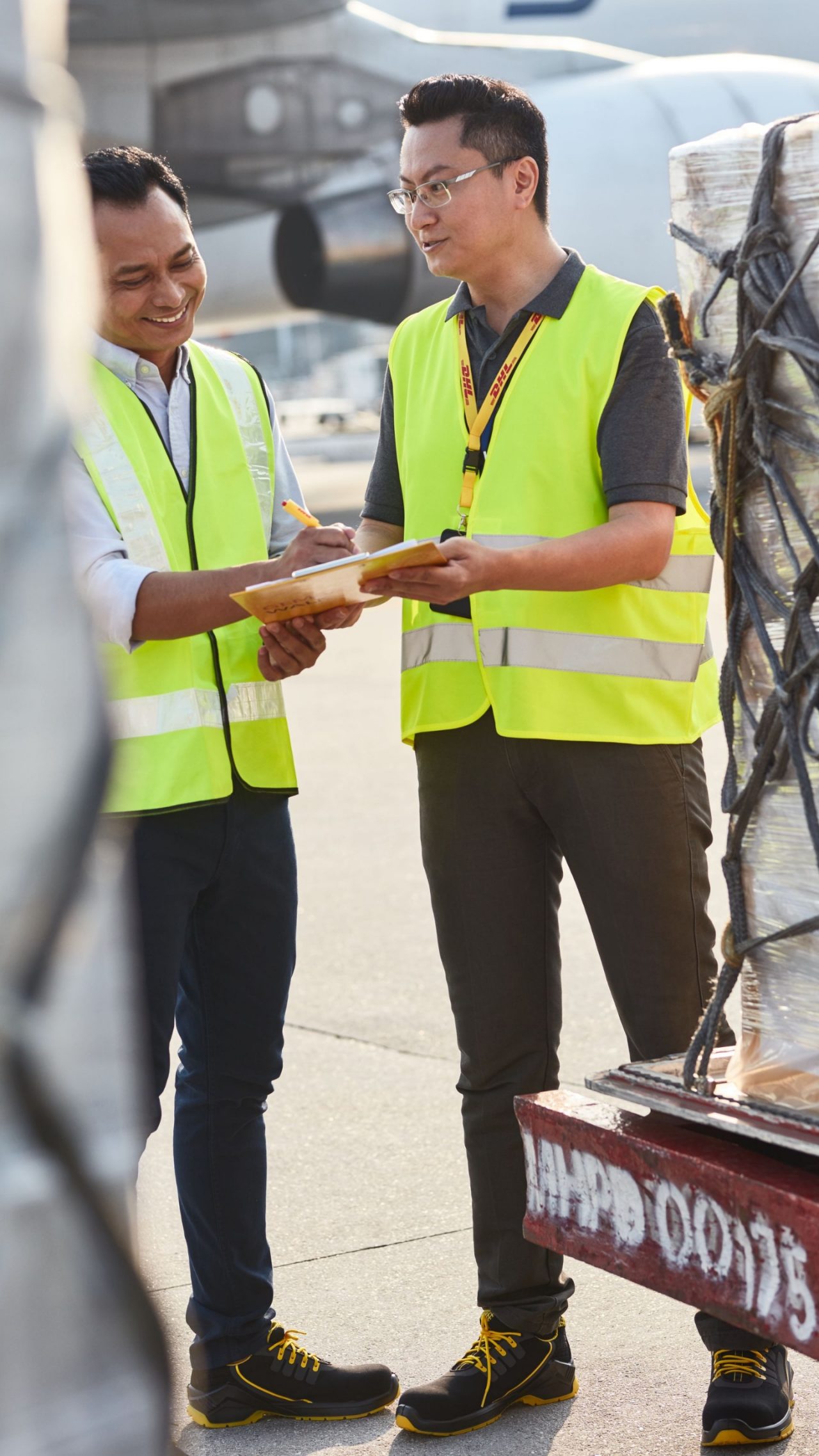 Two DHL Air Freight Employees sign documents at airport tarmac