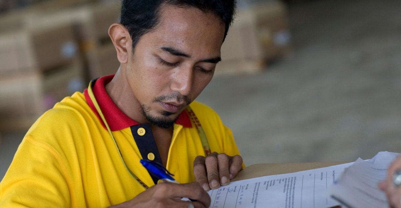 A DHL employee signs a form on a parcel.