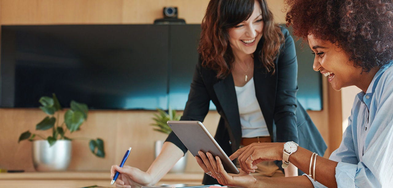 two women smiling at tablet screen