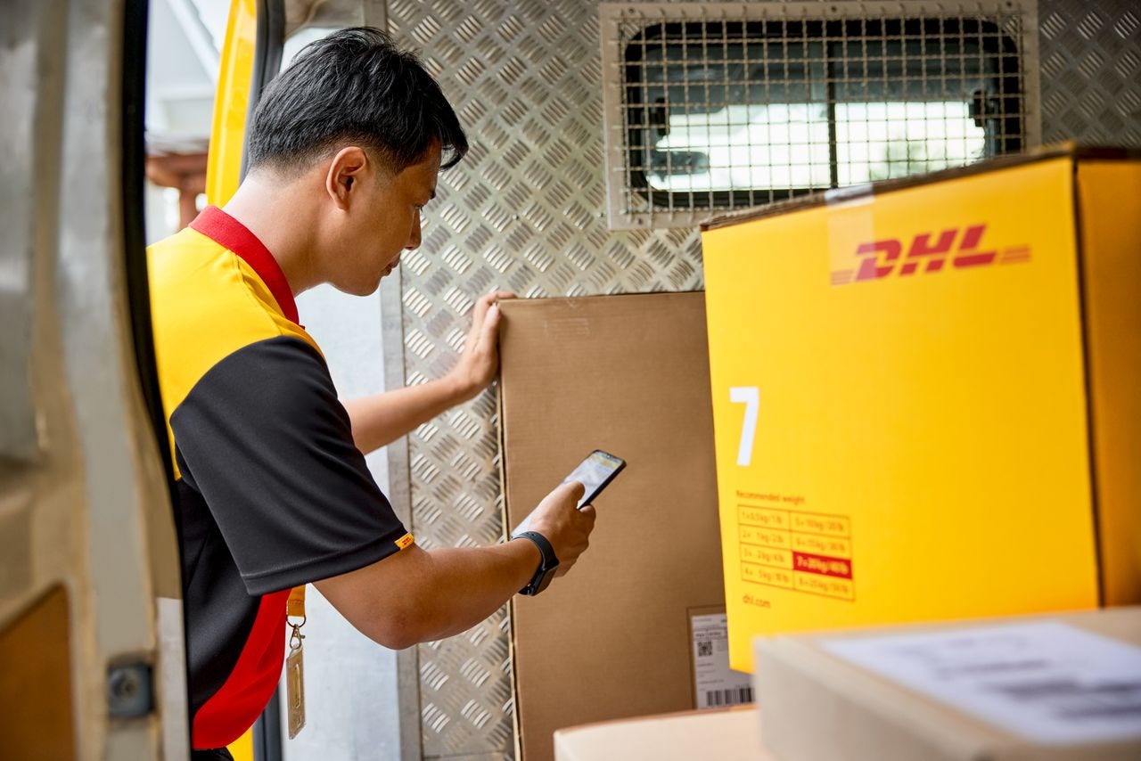 male dhl employee loading parcels onto dhl van