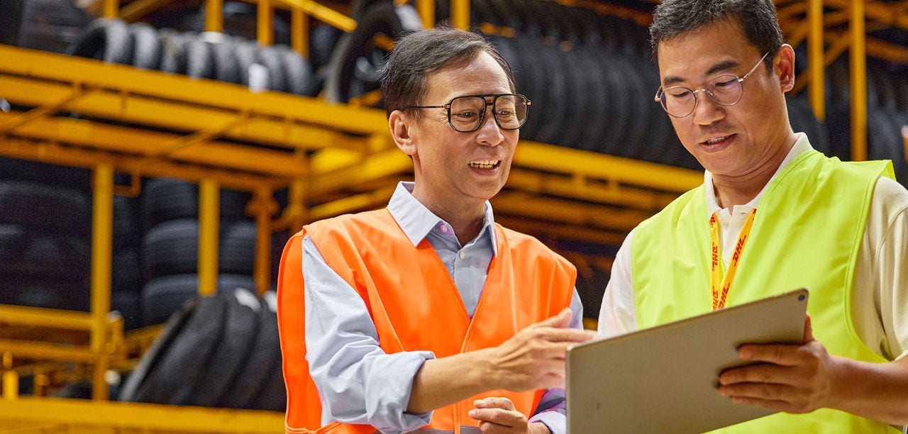 two Asian men in hi vis looking at clipboard