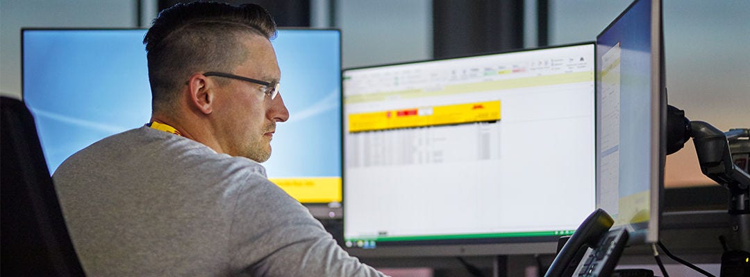 Zaměstnanec DHL se dívá na dvě obrazovky počítačů