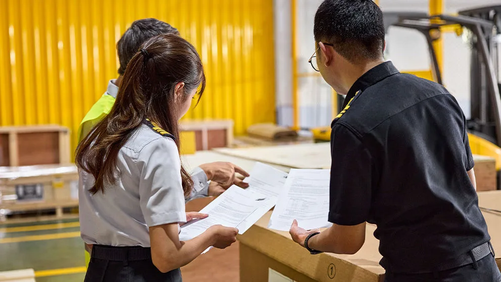 three people looking at paperwork in a warehouse