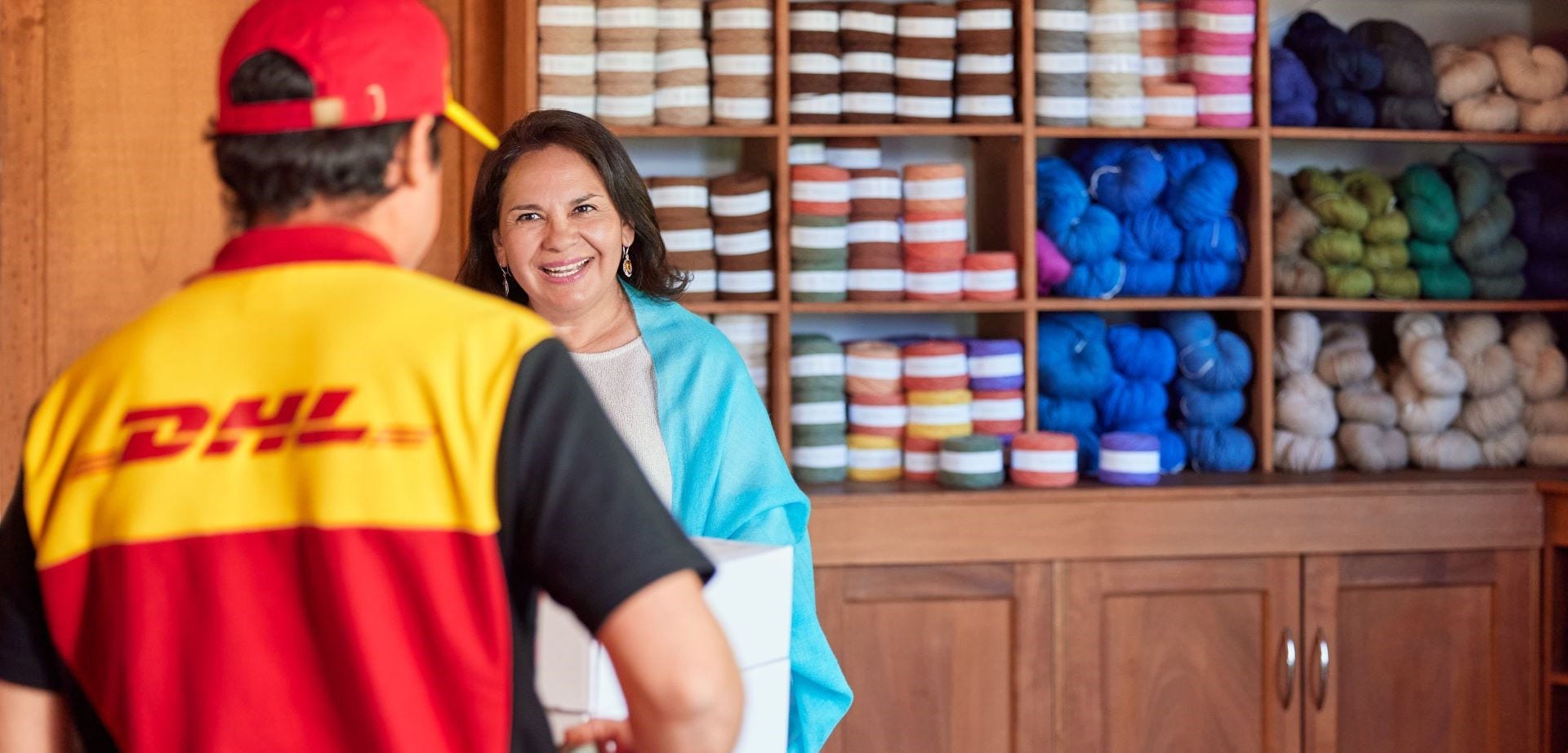 Older woman shop owner handing packages to DHL courier