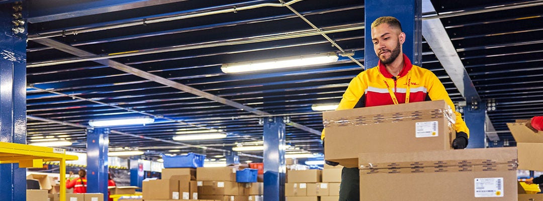DHL worker in a warehouse handling a brown box
