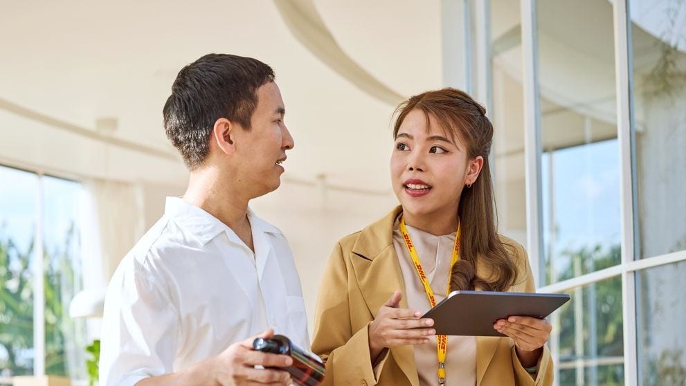a dhl employee showing a male business owner how to export goods from the philippines
