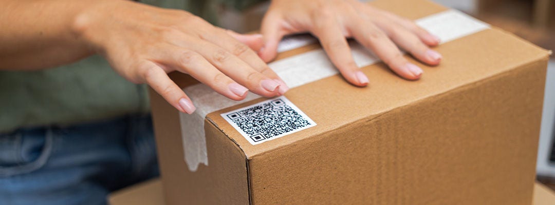 E-commerce at its core: Woman's hands apply a QR code sticker to a package, symbolizing online shopping and shipping. 