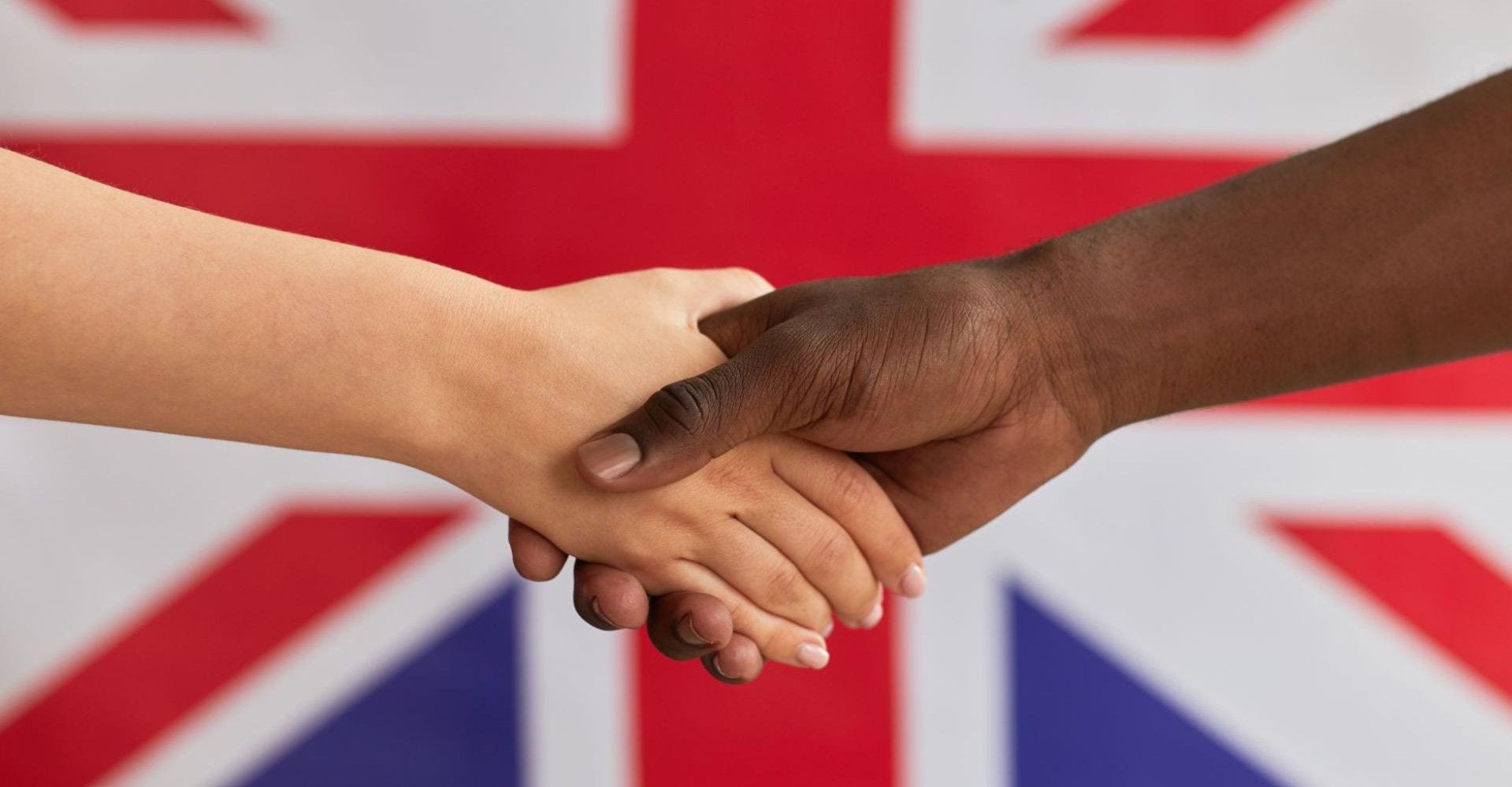Two people shaking hands behind UK flag