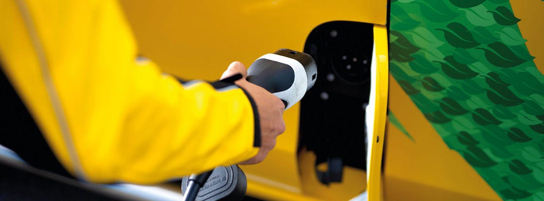 person plugging in a yellow DHL electric vehicle