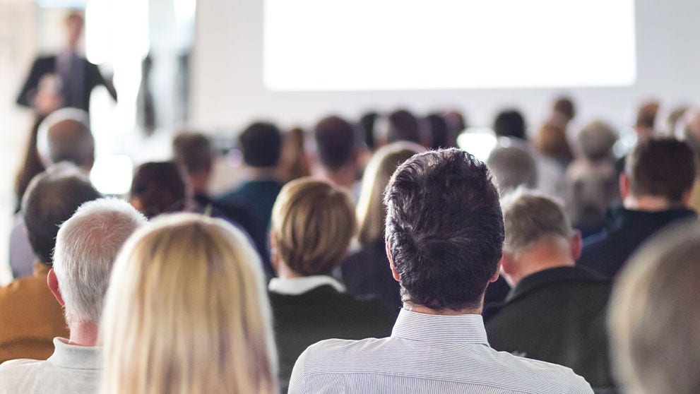 Personas sentadas y poniendo atención en una conferencia