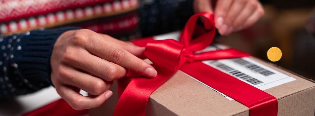 Santa Claus packing present box wrapping gift with red ribbon preparing post shipping delivery parcel.