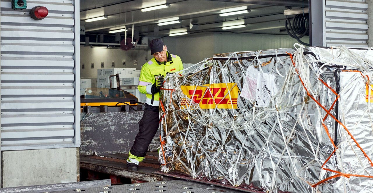  a large and heavy shipment of goods being loaded by a DHL employee