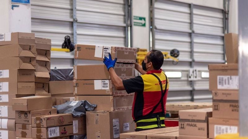 DHL Express employee picks up stacked packages containing Sri Lanka souvenirs