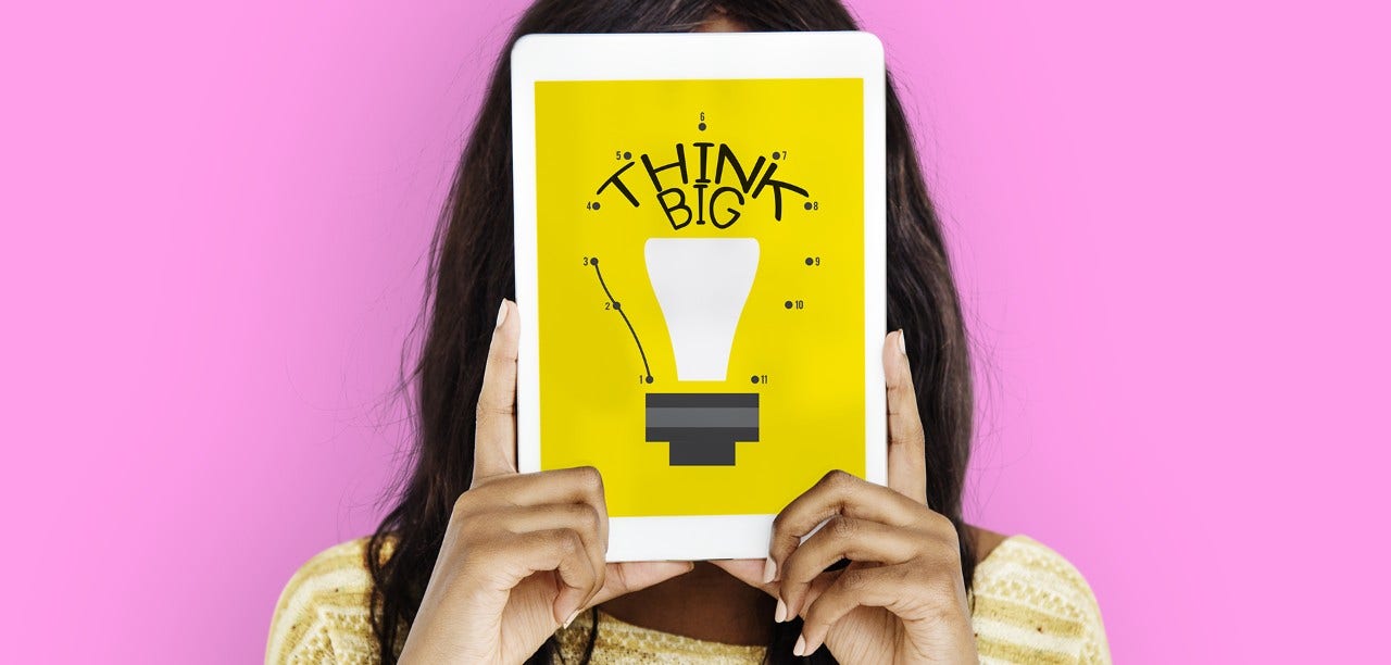 woman holding a tablet with think big written on it