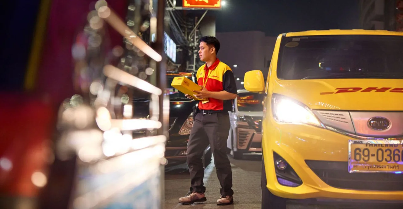 a dhl employee delivering a parcel in an electric delivery van showcasing sustainable logistics solutions