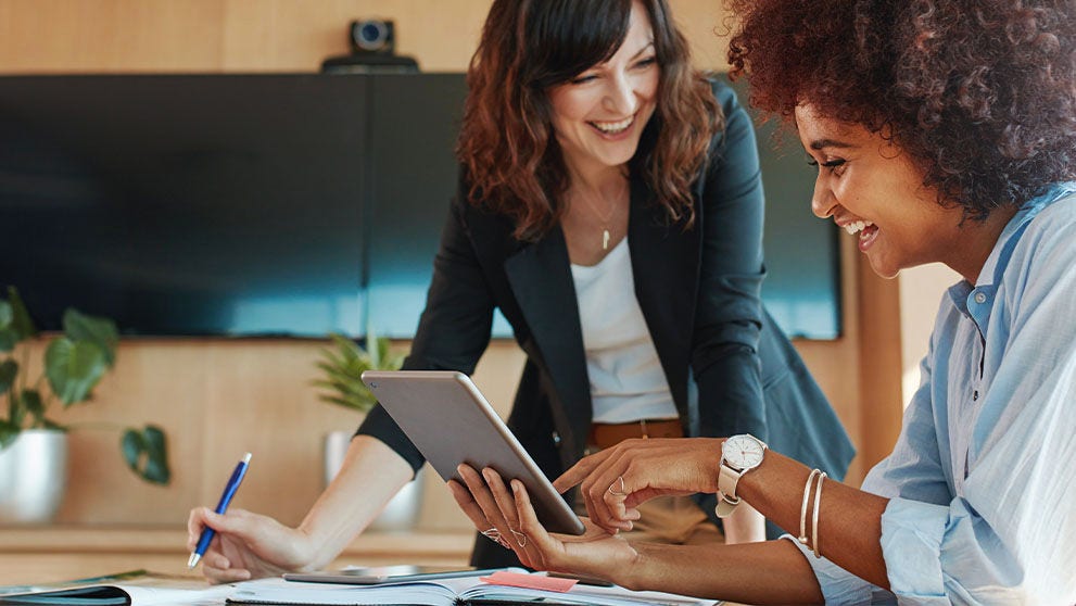 two women smiling at tablet screen