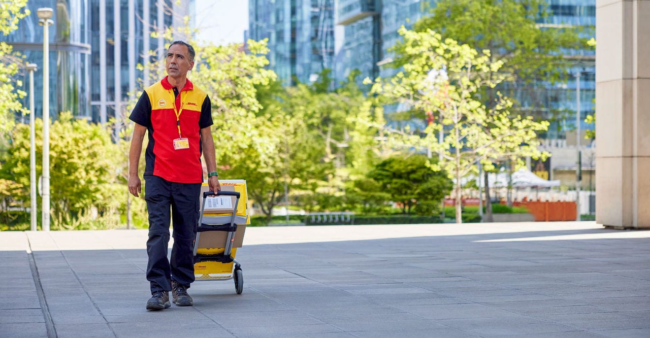 a dhl employee delivering parcels using a hand truck