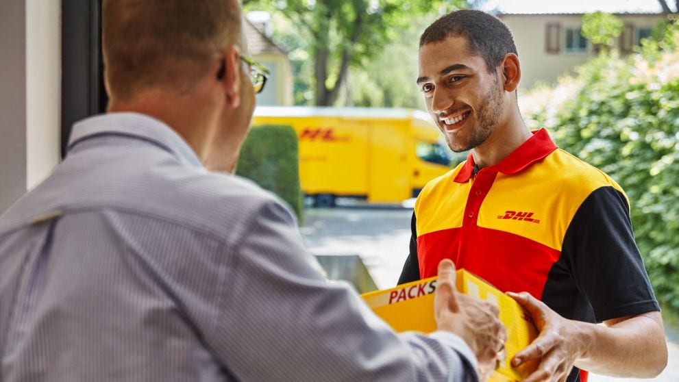Postman gives parcel to man at the front door