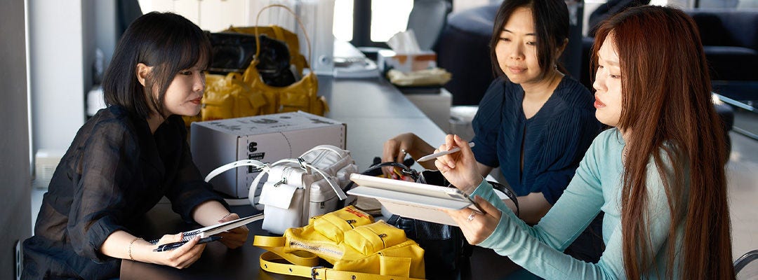 Samo Ondoh success story Three Asian women sitting around a table looking at a branded DHL bag
