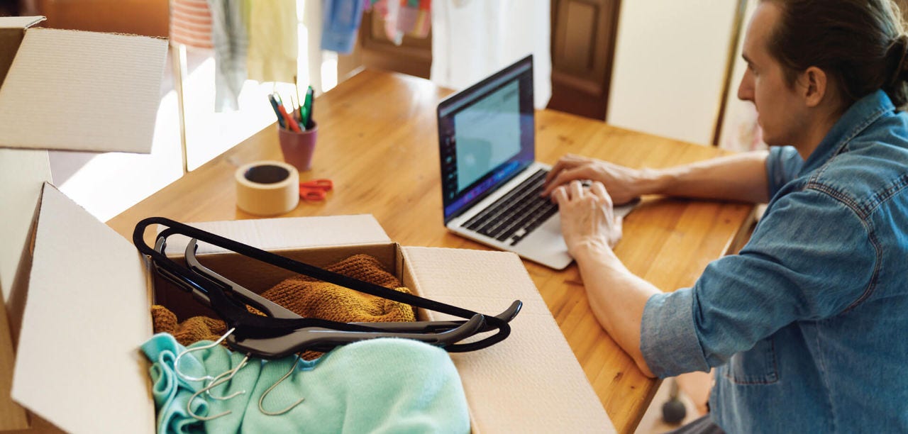 man on his laptop with an open box of clothes next to him