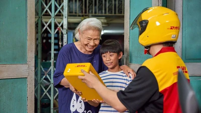 dhl express employee collecting a parcel for shipping from a residential area