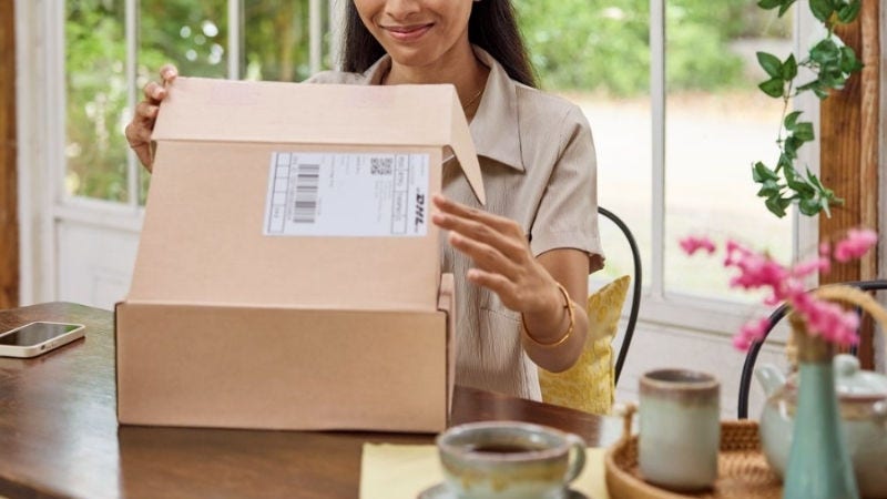 A female customer sits at a table at home and opens her parcel.
