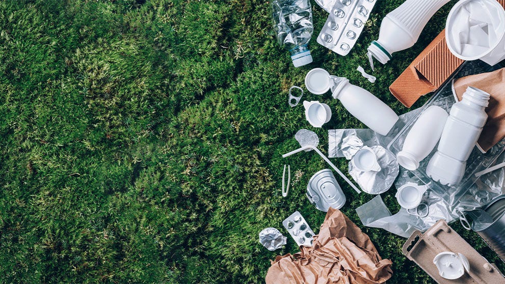Emballage en plastique alimentaire, déchets sur fond de mousse verte après un pique-dans la forêt.