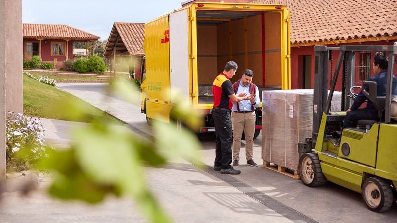 a business owner seen signing on a scanner held by a dhl employee in front of the shipment