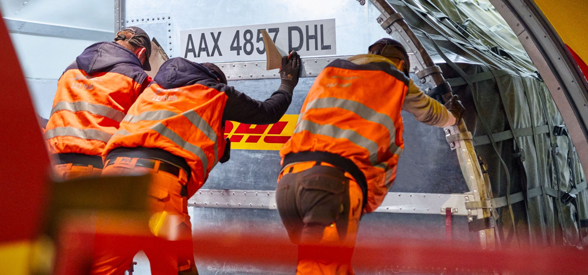 Three DHL workers loading airplane at night