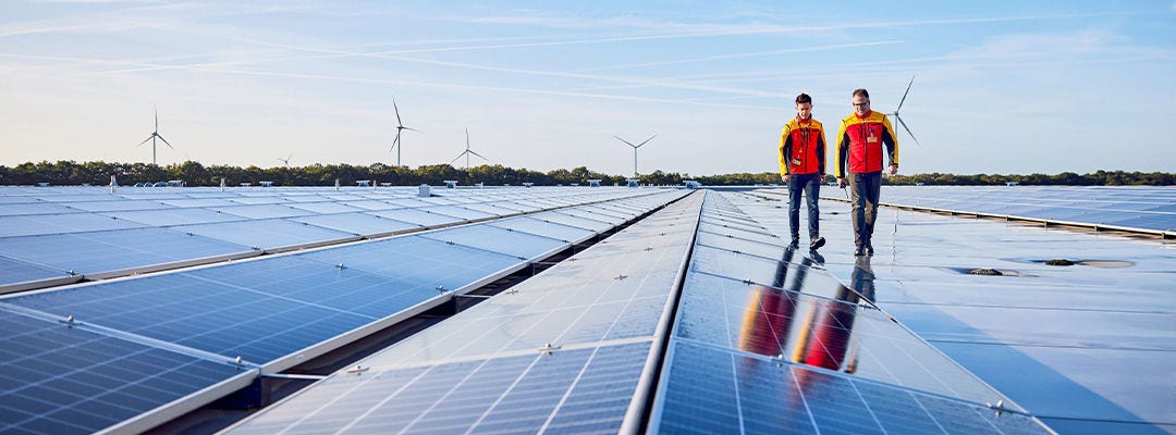two DHL couriers walking on solar panels
