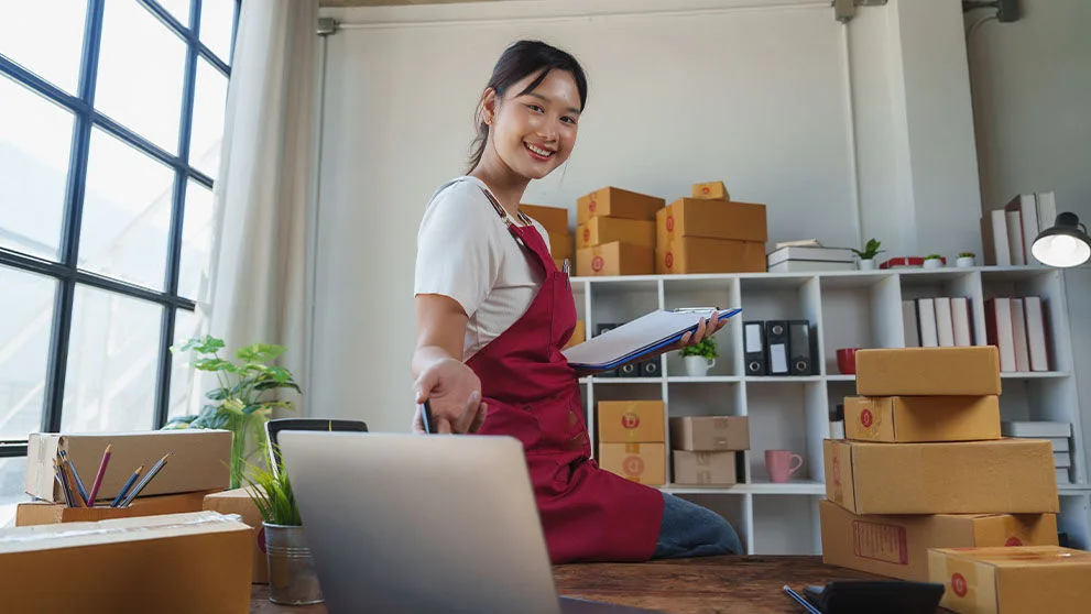 Smiling woman handling packages and orders, running her small online business from home