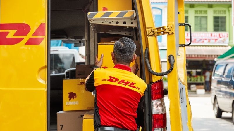 A DHL employee taking a DHL parcel from the van.