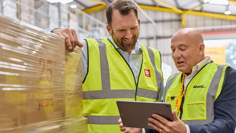 שני עובדי DHL בחולצות היי-ויז מביטים במסך טאבלט