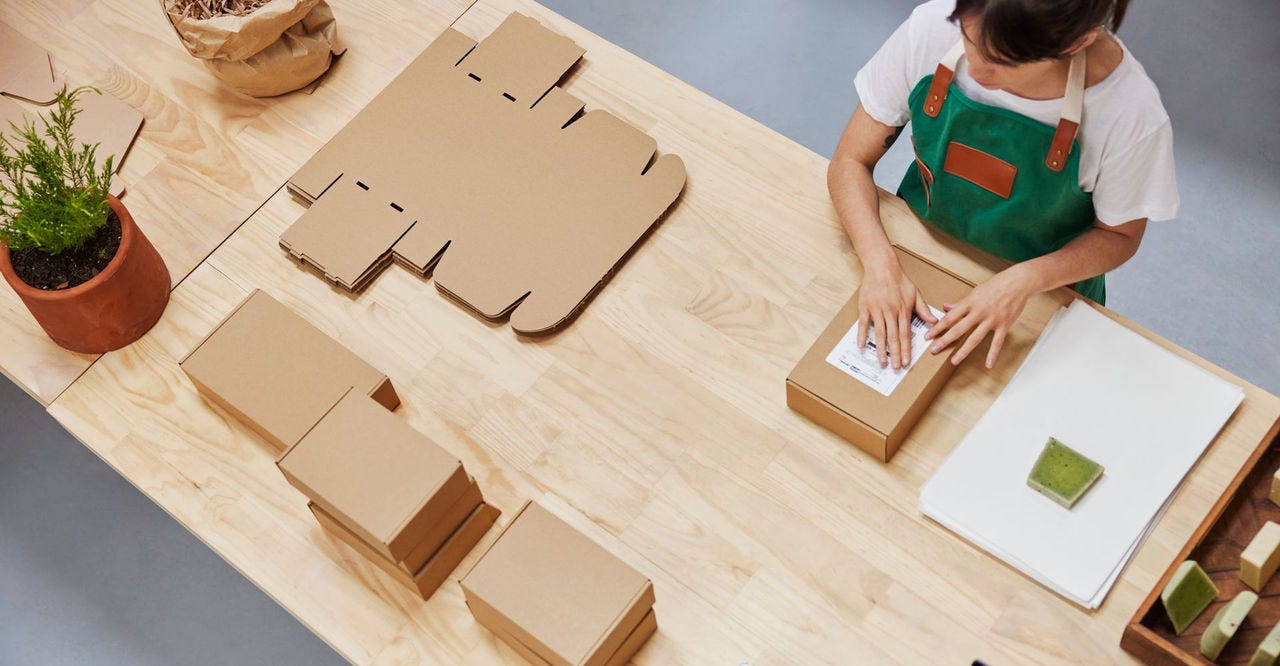 girl packing boxes with sustainable materials to promote carbon insetting