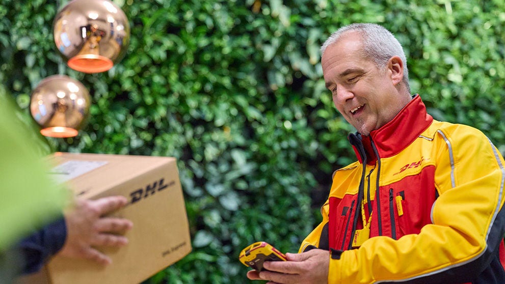 DHL courier scanning a brown DHL box