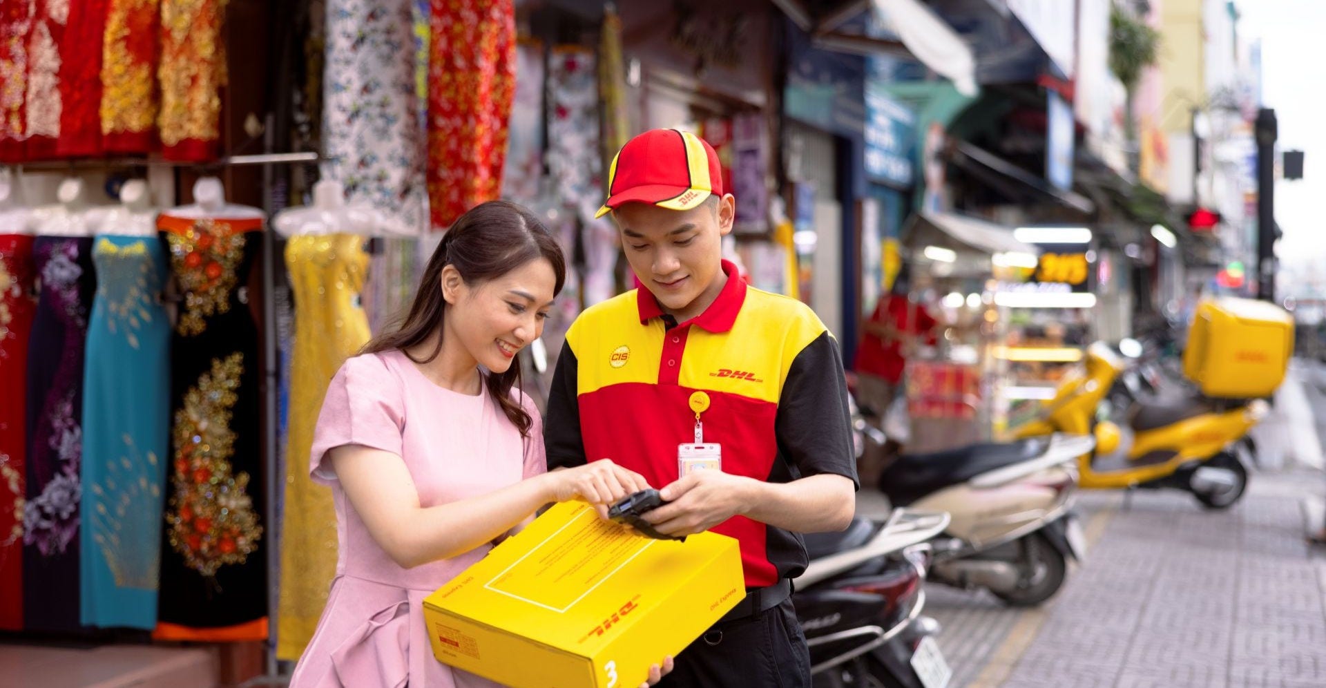 female business owner handing garment parcel to  dhl employee for shipping