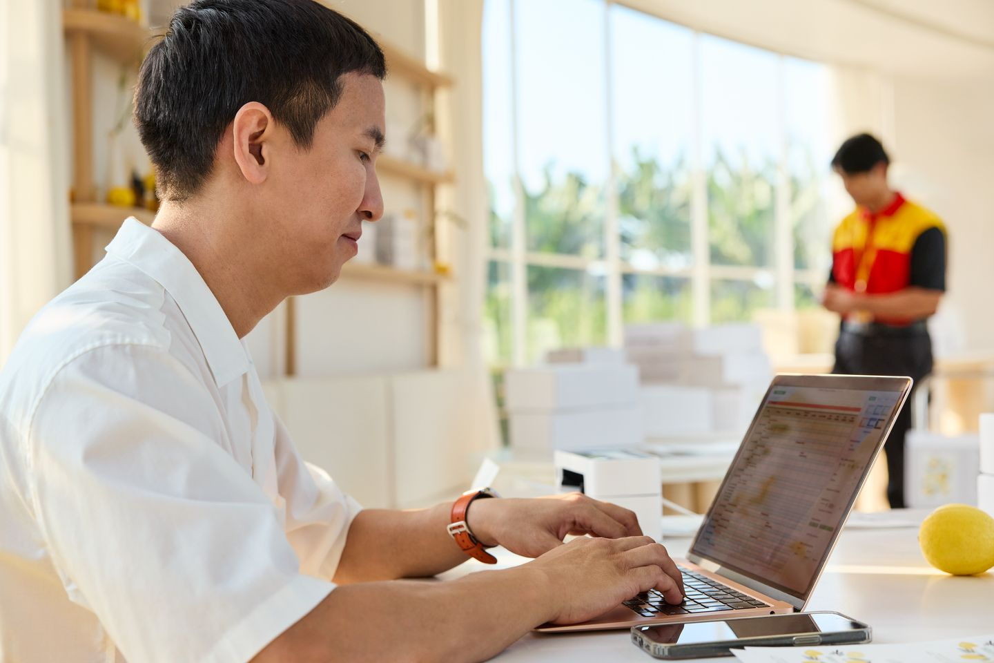 The owner of a sustainable shop is working at his desk in the foreground.