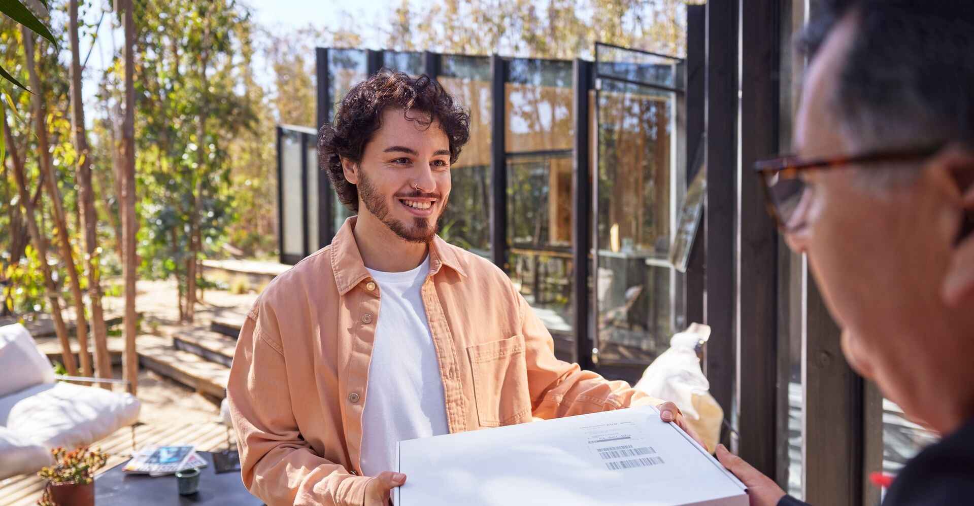 A DHL employee hands a parcel over to a male customer.