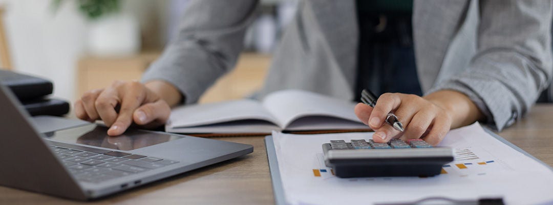 Personne qui glisse sur un ordinateur portable et tapote sur une calculatrice